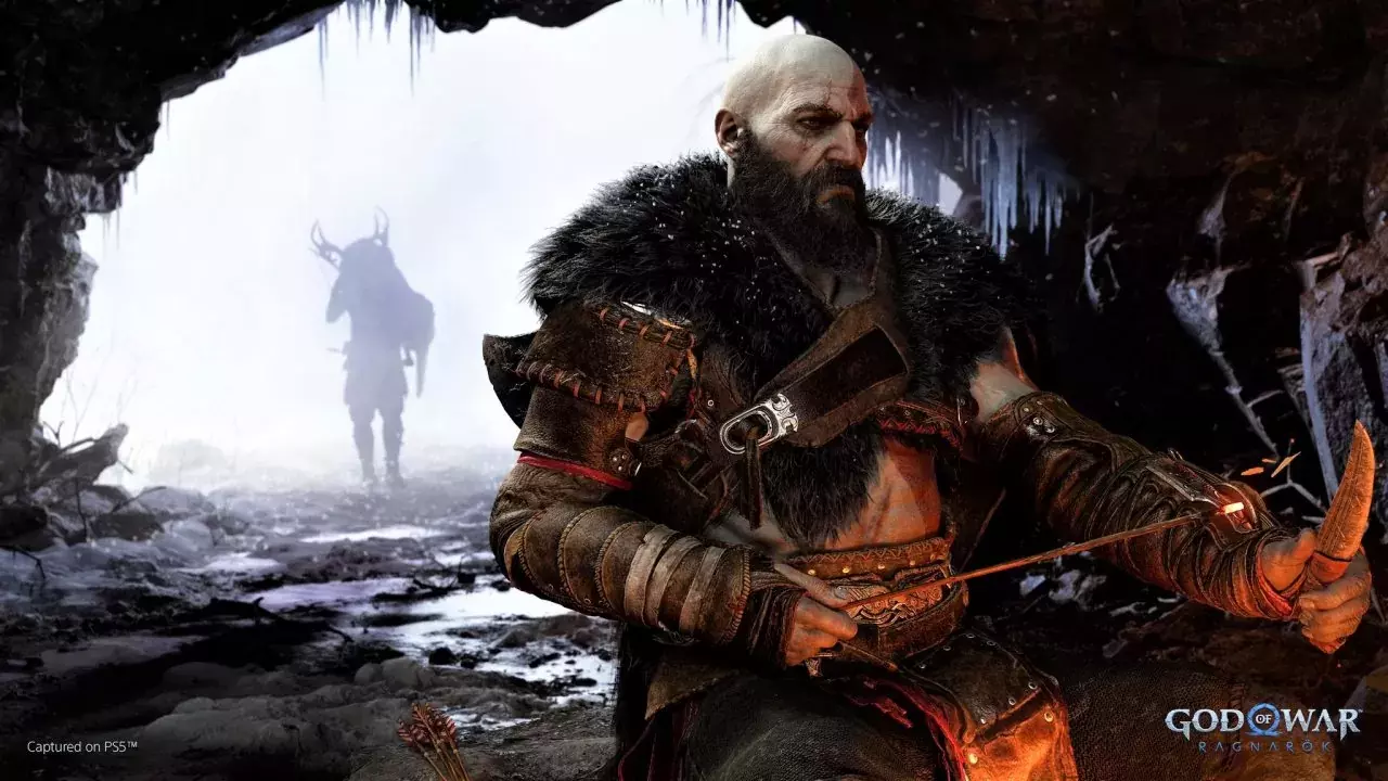Kratos sitting in a cave, Atreus is in the background carrying a deer